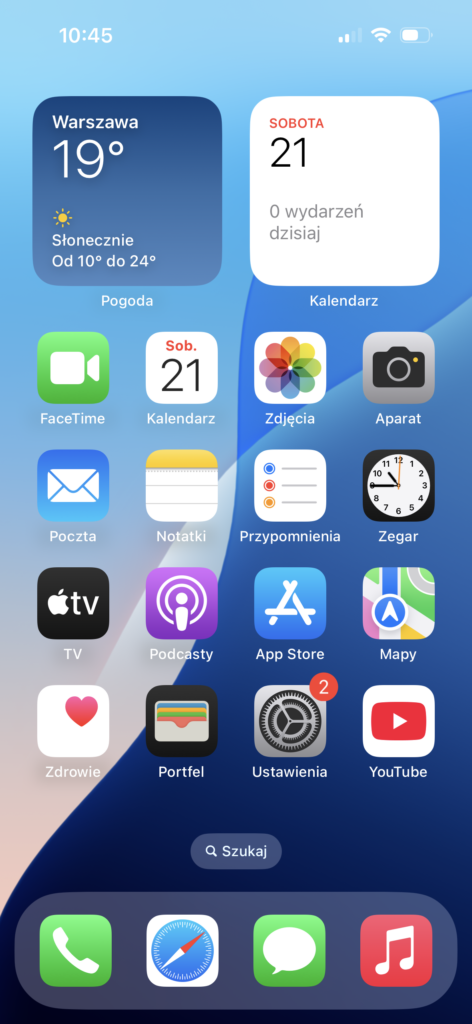 Ekran główny iPhone'a z systemem iOS w języku polskim, z ikonami aplikacji i widżetami pogody i kalendarza.
